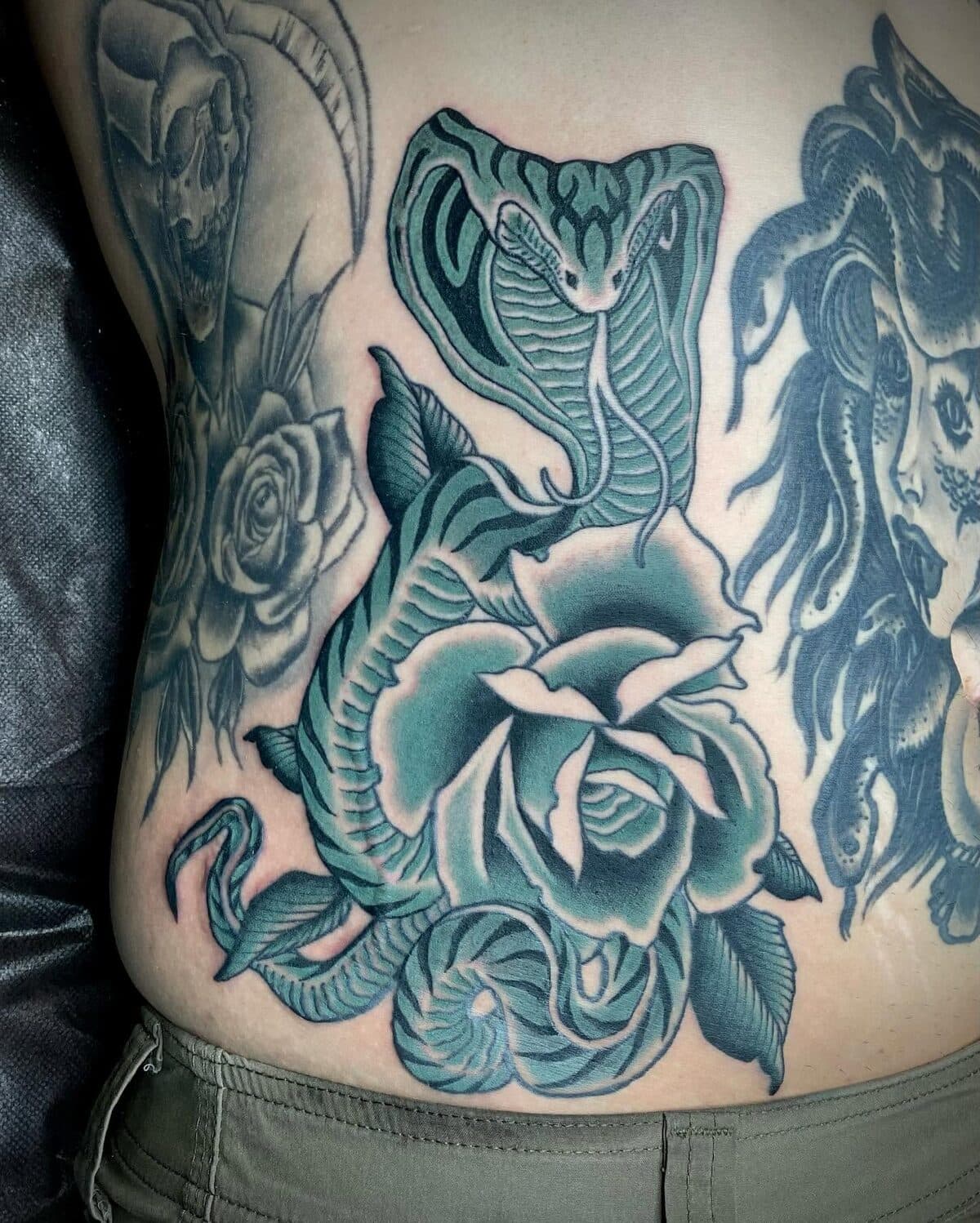 Cobra and roses torso tattoo in blue and black ink