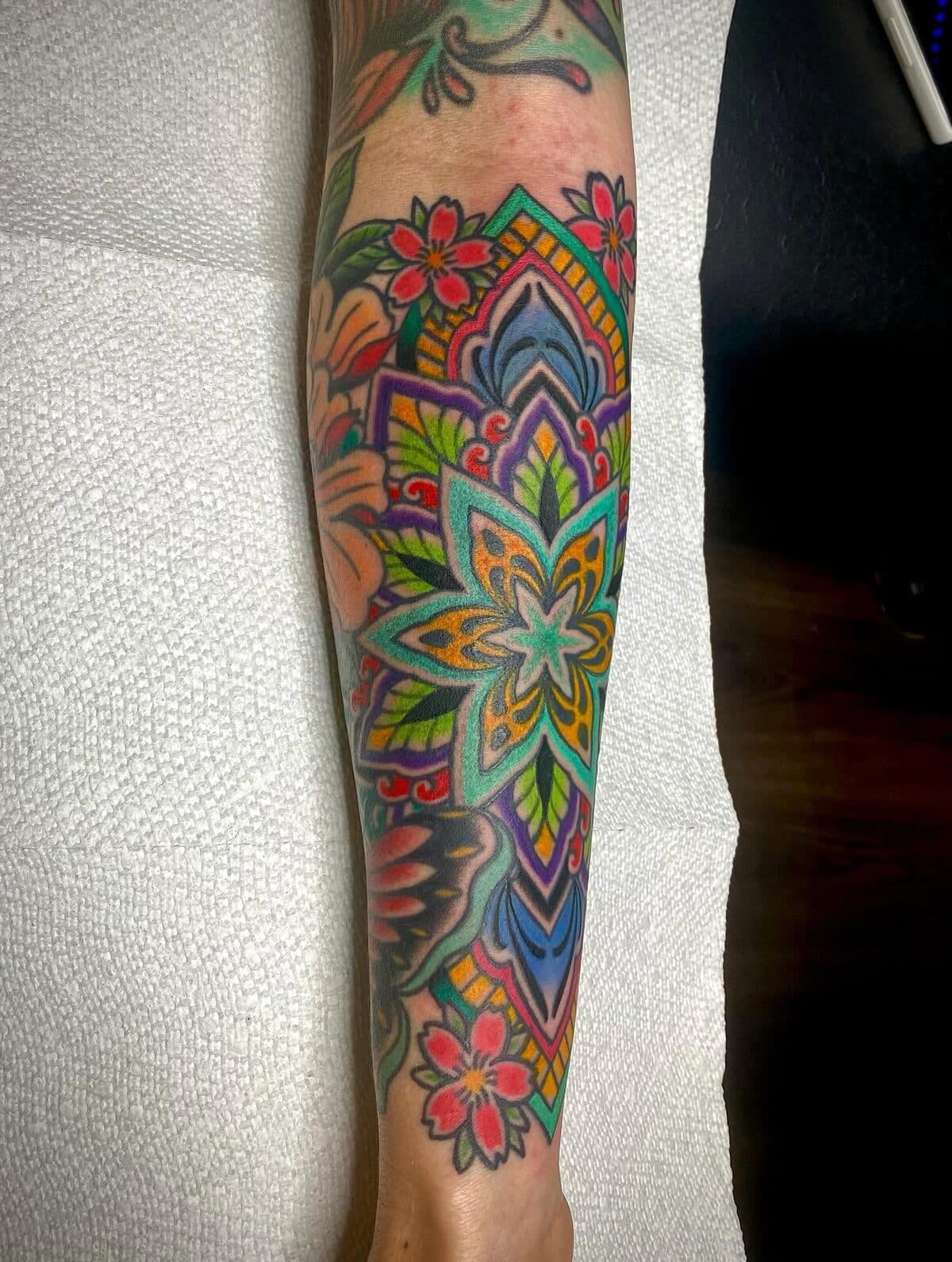 Vibrant multi-colored mandala and floral forearm tattoo