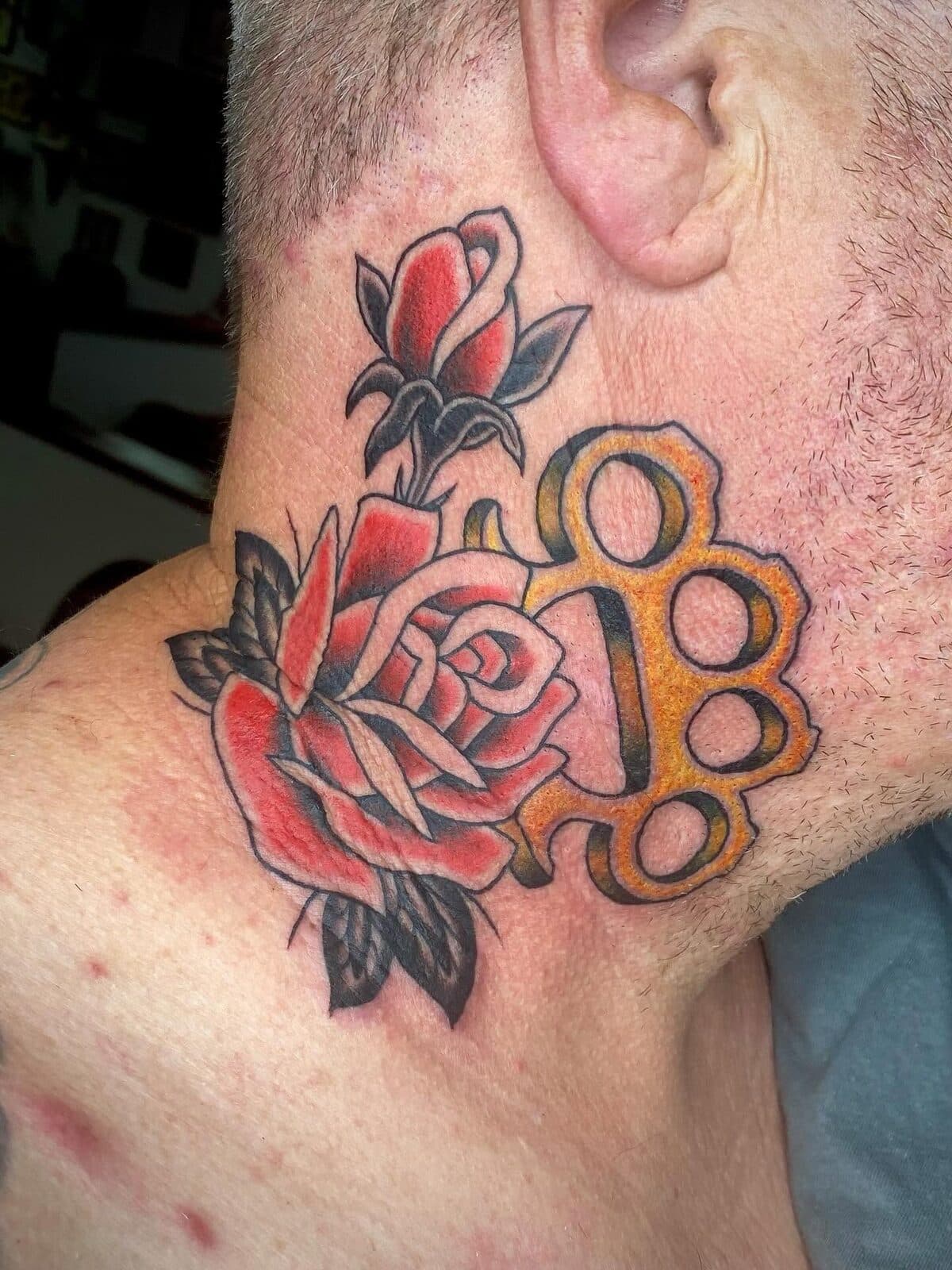 Red roses with brass knuckles neck tattoo