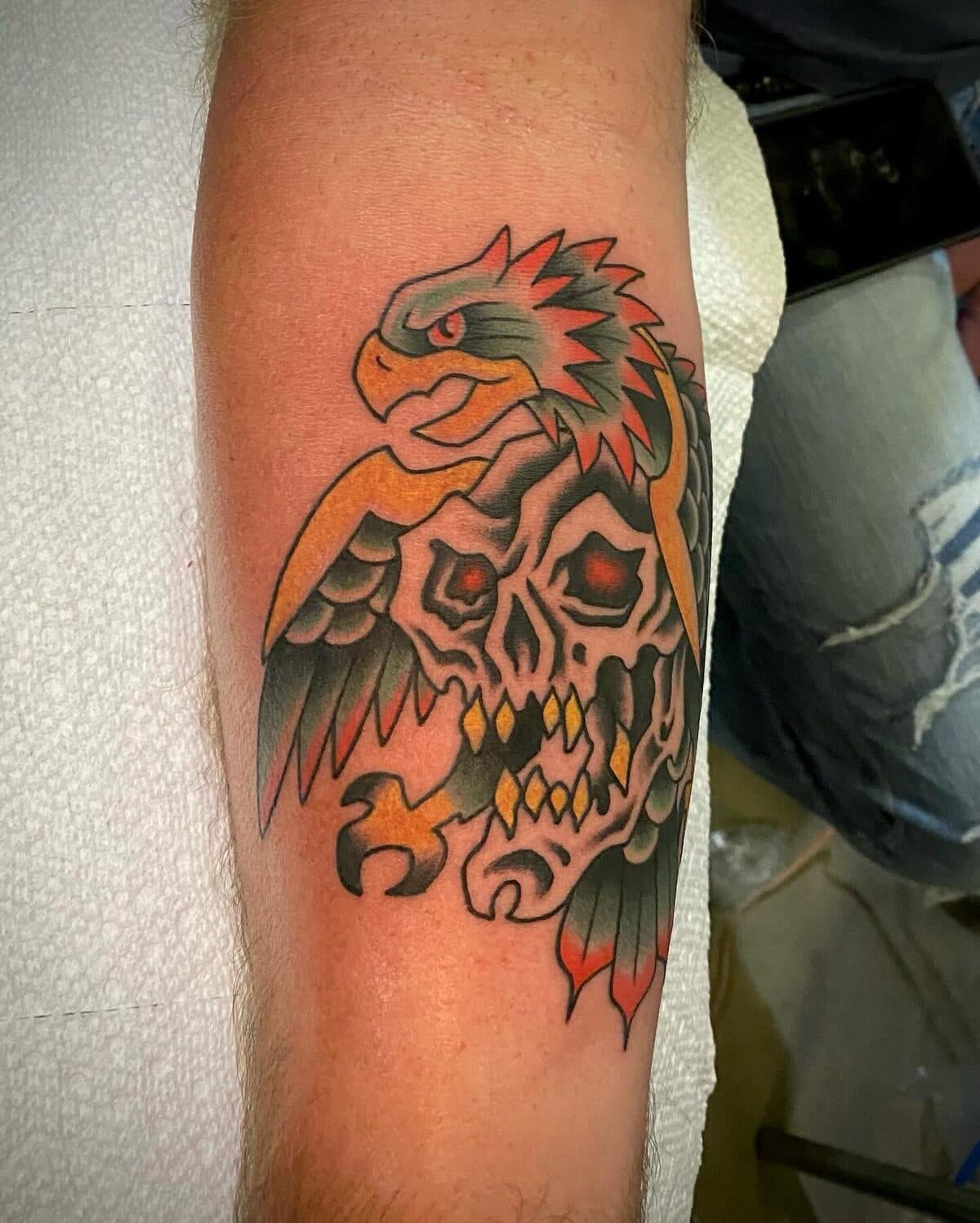 Traditional eagle and skull tattoo in orange, red, and black
