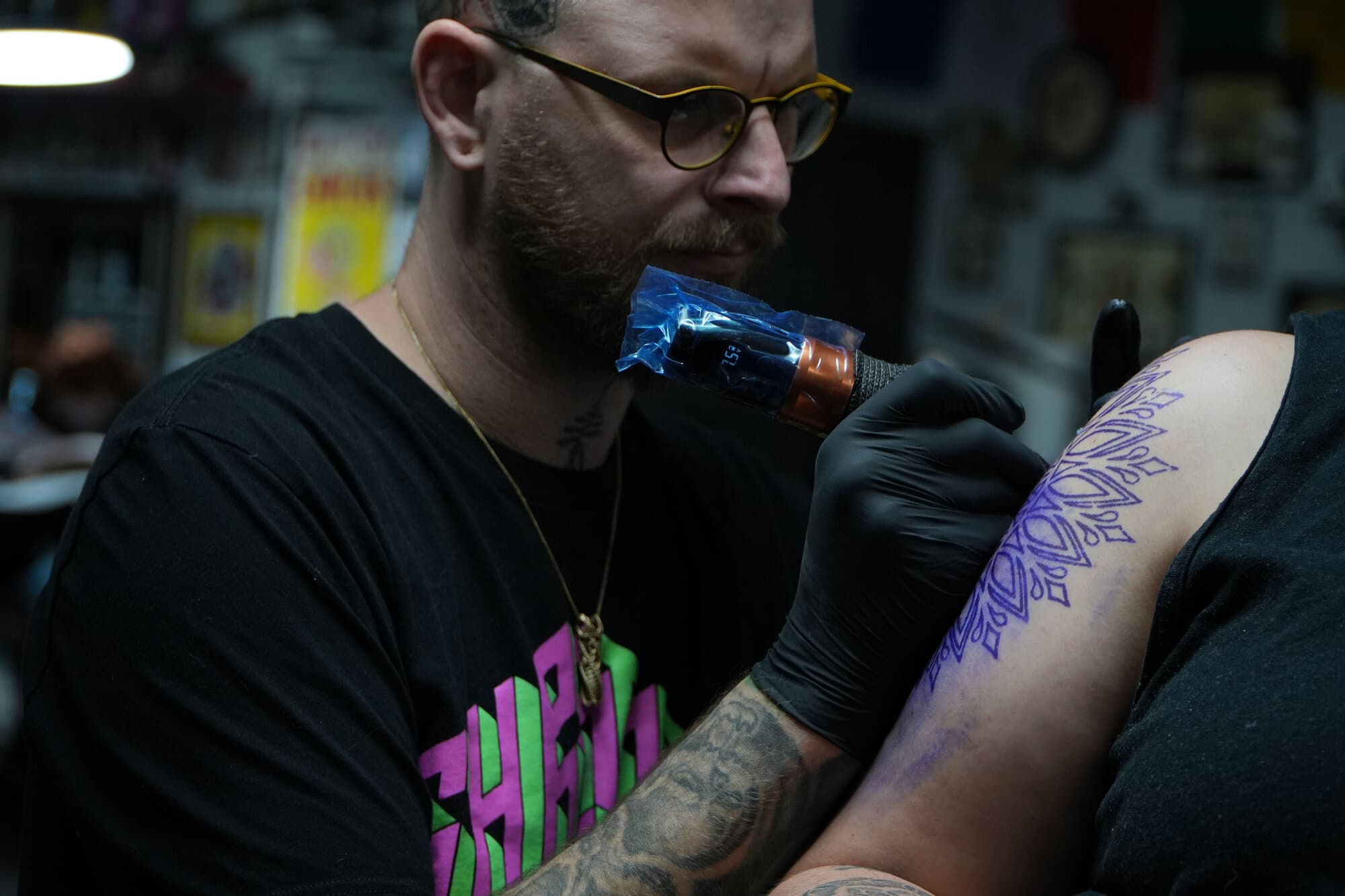 Joe Dean lining a geometric mandala tattoo on a client's upper arm
