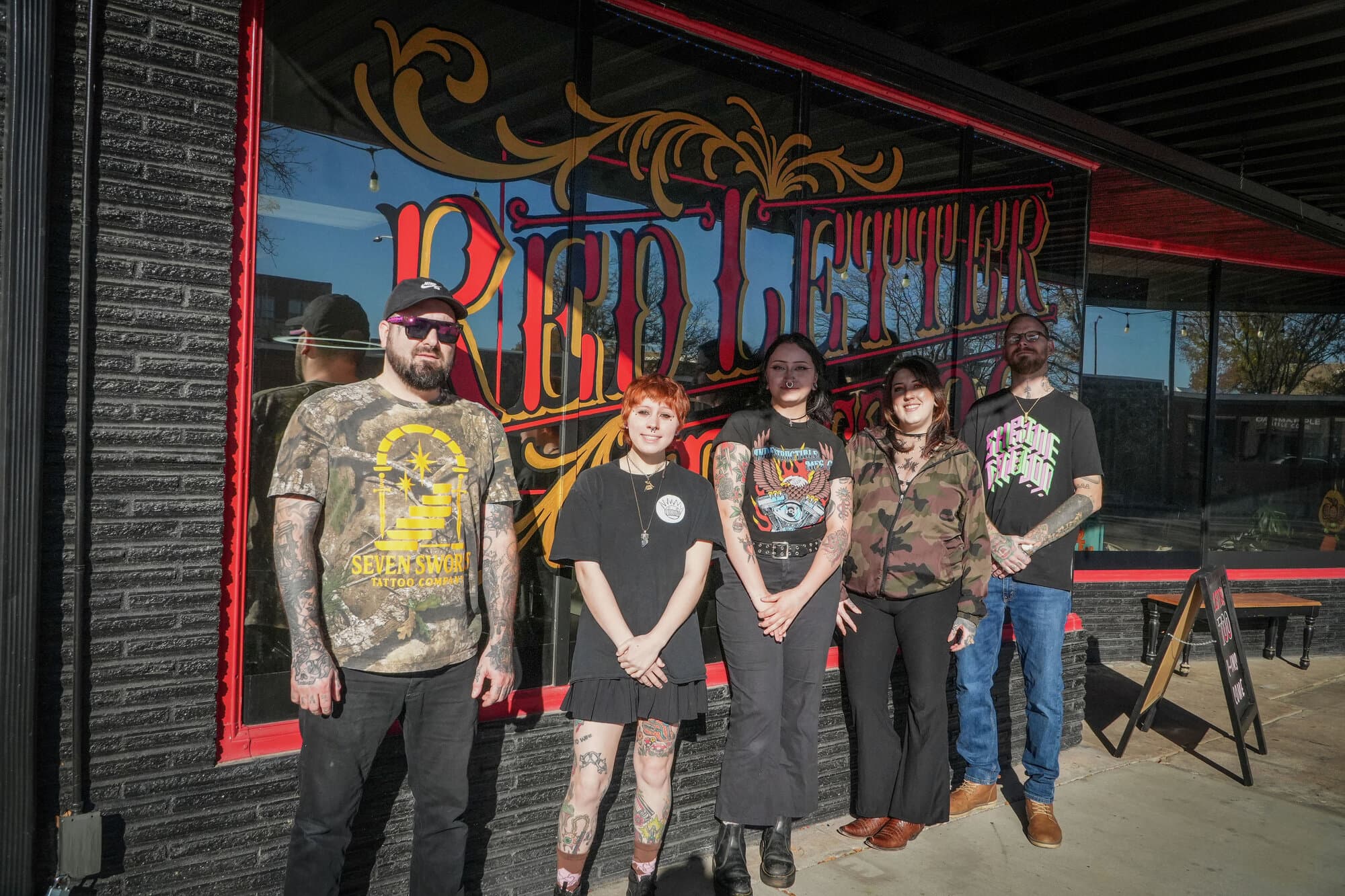 The Red Letter Tattoo crew lined up in front of the shop's hand-painted window