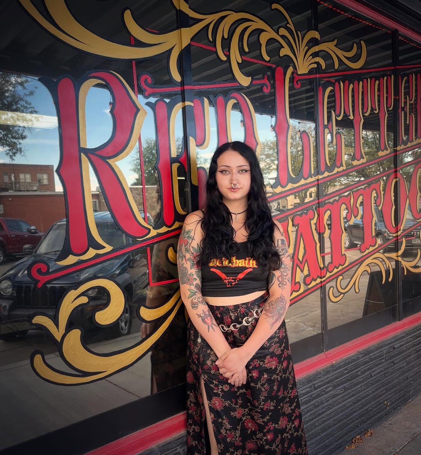 Tattooed client in front of the hand-painted Red Letter Tattoo window