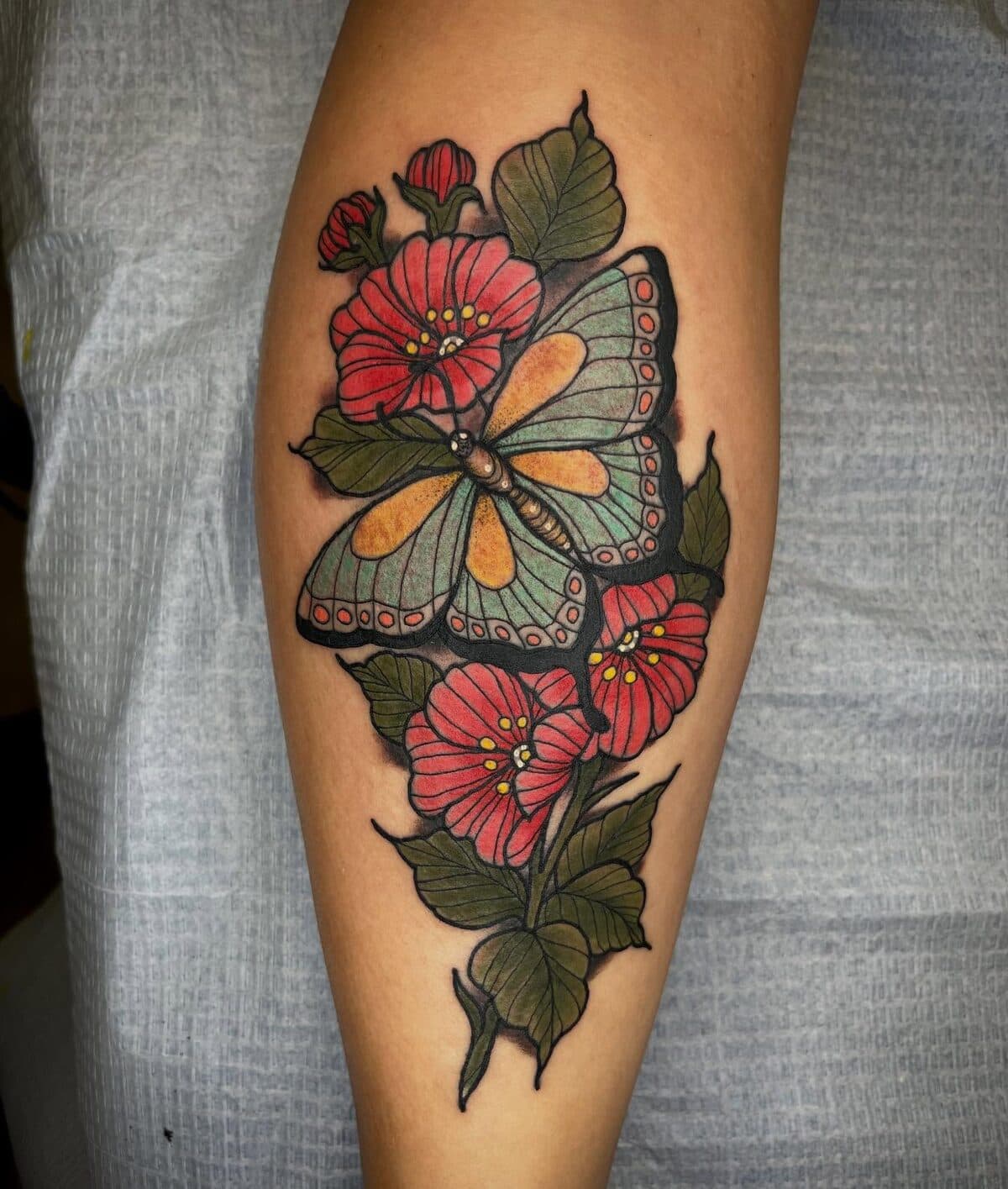 Butterfly perched on red flowers leg tattoo